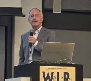 Michael Walz, TÜV SÜD Life Service speaking at a podium at the German...