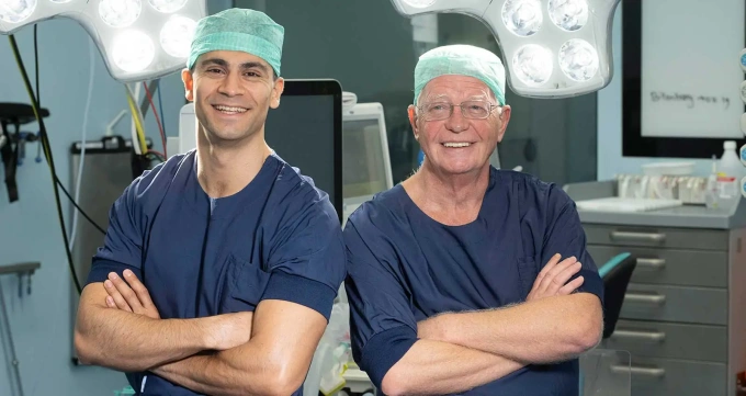 Two surgeons in the OR posing and smiling for the camera next to each other...