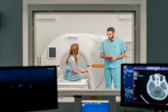 A radiology technologist speaks with a patient before a CT scan in the imaging...