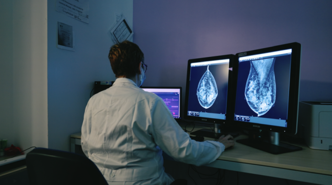 Radiologist sitting at a workstation reviewing breast cancer screening...