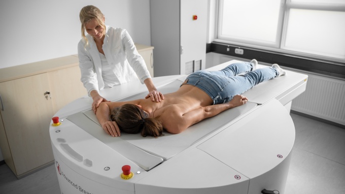 A patient lies face down on the nu:view breast CT scanner while a medical...