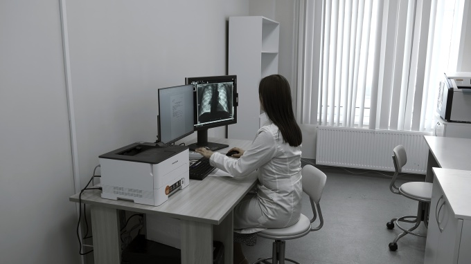 Radiologist viewing chest X-ray images on two monitors at a desk...