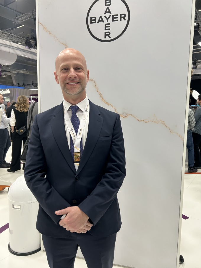 Man with arms folded in front of him in a suit smiling at the camera at an event...