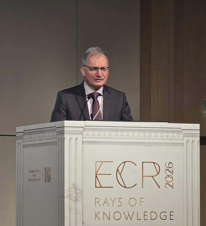 Man on a stage standing behind a speaker podium while talking: Professor...