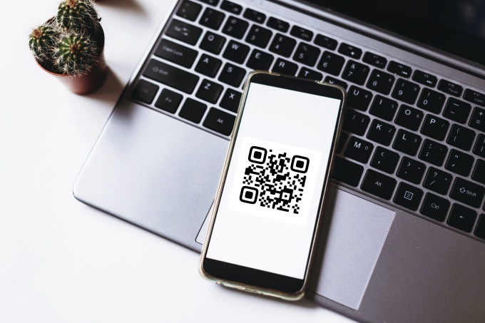 Mobile phone showing a QR code lying on a laptop